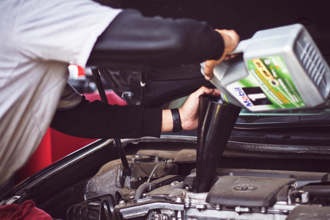 Photo by Tim Mossholder man refilling motor oil on car engine bay